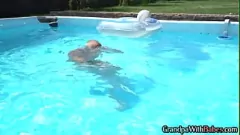 Odtwórz Szczęśliwa seniorka robi bujnej blondynce laskę na świeżym powietrzu przy basenie, wykonując ruch na pieska i obciąganie